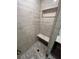 Shower with light gray marble style tile, built-in shelving, bench seating, and hexagon-tiled floor at 3505 Gloria Ave, Plant City, FL 33563