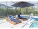 Exterior shot of pool-side sun-loungers with umbrellas, pool and a basketball hoop at 3850 Bonfire Dr, Odessa, FL 33556