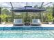 Tranquil screened-in pool area featuring lounge chairs under an umbrella, offering a serene retreat at 3850 Bonfire Dr, Odessa, FL 33556