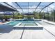 Pool with an in-ground spa, lounge chairs, and umbrellas in a screened enclosure at 3850 Bonfire Dr, Odessa, FL 33556