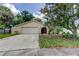 Charming single-story home featuring a two-car garage, arched entryway, and mature landscaping at 4908 Rockledge Cir, Tampa, FL 33624