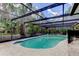 A sparkling swimming pool with a screened enclosure, surrounded by lush tropical landscaping at 4908 Rockledge Cir, Tampa, FL 33624