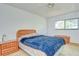 A bedroom with light walls, an upholstered bed with a blue comforter, and matching wood bedside tables at 4911 Country Aire Ln, Tampa, FL 33624