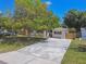Home exterior featuring a long driveway, lush green lawn, and mature trees at 5010 8Th N Ave, St Petersburg, FL 33710