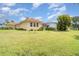 Exterior shot of a tan home, tile roof, screened in pool, and large lawn and landscaping at 6120 9Th Avenue Ne Cir, Bradenton, FL 34212