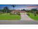 Stunning single-story home with a brick-paved driveway, terracotta roof, lush green lawn, and beautiful palm trees at 6120 9Th Avenue Ne Cir, Bradenton, FL 34212