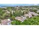 Scenic aerial view of a residential neighborhood with a glimpse of the ocean in the distance, surrounded by lush trees at 120 Colony South Dr, Tarpon Springs, FL 34689