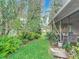Side view of a home with a green lawn and lush landscaping featuring trees, ferns and flowering plants at 120 Colony South Dr, Tarpon Springs, FL 34689