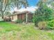 Back view of a home, showcasing a screened lanai and a well-maintained lawn with garden beds and trees at 120 Colony South Dr, Tarpon Springs, FL 34689