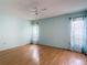 Bedroom with wood laminate flooring, two windows with curtains, and a ceiling fan at 120 Colony South Dr, Tarpon Springs, FL 34689