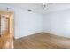 Empty bedroom with wood laminate flooring, ceiling fan, and a doorway leading to an adjacent bathroom at 120 Colony South Dr, Tarpon Springs, FL 34689