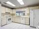 Traditional kitchen featuring white cabinetry, appliances, and view to another room at 120 Colony South Dr, Tarpon Springs, FL 34689