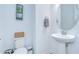 Elegant half bathroom with a pedestal sink, round mirror, and a neutral color palette at 12902 Brookside Moss Dr, Riverview, FL 33579