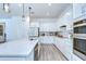 Modern kitchen featuring white cabinets, stainless steel appliances, and a large center island with pendant lighting at 12902 Brookside Moss Dr, Riverview, FL 33579