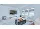 Living room featuring three large windows, comfortable chairs, a dark wood coffee table, and a large TV at 12902 Brookside Moss Dr, Riverview, FL 33579