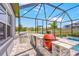 Outdoor kitchen with grill, mini fridge, sink, and counter seating overlooking the pool at 12902 Brookside Moss Dr, Riverview, FL 33579