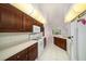Kitchen featuring wood cabinetry, white appliances, and sleek lighting, complemented by white tile flooring at 13819 Stoneridge Dr, Hudson, FL 34669