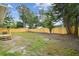 Large, partially-fenced backyard with some sparse grass and many trees at 1801 E Navajo Ave, Tampa, FL 33612