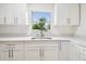Well-lit kitchen features modern white cabinets and quartz countertops beneath a window at 1801 E Navajo Ave, Tampa, FL 33612