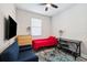 Cozy bedroom with light wood floors, red comforter and dark blue futon at 19323 Hawk Valley Dr, Tampa, FL 33647
