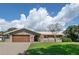 Charming single-story home with a brick and light-colored exterior, a well-manicured lawn and a two-car garage at 2017 Iowa Ne Ave, St Petersburg, FL 33703