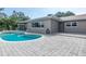 This is a view of the backyard pool with a gray stone patio and screen porch at 2017 Iowa Ne Ave, St Petersburg, FL 33703