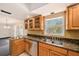Classic kitchen featuring stainless steel appliances, granite countertops, and wooden cabinetry, adjacent to dining area at 202 Mindy Dr, Largo, FL 33771