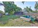 Large, fenced backyard featuring green lawns, a screen enclosed patio, and garden beds at 22115 Laver Ln, Land O Lakes, FL 34639