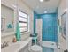 Bright bathroom featuring a walk-in shower with blue tile, white fixtures, and a stylish modern design at 22115 Laver Ln, Land O Lakes, FL 34639