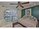 A well-lit room with an arch window, ceiling fan, floral bedding, and hardwood floors at 22115 Laver Ln, Land O Lakes, FL 34639
