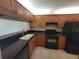 Kitchen featuring solid countertops, wood cabinetry, black appliances, and stainless faucet at 2424 W Tampa Bay Blvd # M-201, Tampa, FL 33607