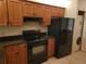 Kitchen with wood cabinets, black appliances, and adjacent laundry area at 2424 W Tampa Bay Blvd # M-201, Tampa, FL 33607