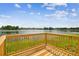 Scenic lake view from wooden deck and railing, with lush greenery and blue skies at 3205 Pleasant Lake Dr, Tampa, FL 33618
