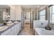 This elegant bathroom features double sinks, granite countertops, tile floors, a glass-enclosed shower, and a soaking tub at 32442 Osprey Peak Way, San Antonio, FL 33576