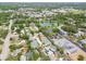 Expansive aerial view showcases a residential neighborhood with lush greenery, a tranquil lake, and nearby community amenities at 361 Colonial Ct, Dunedin, FL 34698