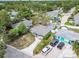 An aerial view of a quaint single-story home featuring a driveway and a lush, tree-filled neighborhood at 361 Colonial Ct, Dunedin, FL 34698