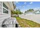 View of backyard with partial view of house, white fencing, and green grass at 361 Colonial Ct, Dunedin, FL 34698
