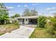 Quaint single-story home with a carport and lush greenery, providing curb appeal at 361 Colonial Ct, Dunedin, FL 34698