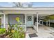 Close up on charming front porch with bench seating, plants, and a carport at 361 Colonial Ct, Dunedin, FL 34698
