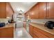 Galley kitchen featuring wood cabinets, tile floors, stone countertops, stainless steel appliances, and a window over the sink at 4326 Great Lakes N Dr, Clearwater, FL 33762