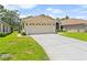 Two-car garage with ample driveway space complemented by manicured landscaping and a well-maintained lawn at 521 Bent Oak Ct, Spring Hill, FL 34609