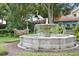 Serene scene of Armston Park's water fountain with decorative herons, surrounded by lush greenery and mature trees at 556 Virginia St, Dunedin, FL 34698