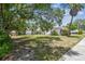 This property features a lush front yard with mature trees and landscaping at 556 Virginia St, Dunedin, FL 34698