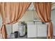 Laundry area equipped with washer, dryer, and water heater, complemented by privacy curtains at 556 Virginia St, Dunedin, FL 34698