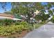 Street view of stores under shady trees with a railroad crossing sign in view at 556 Virginia St, Dunedin, FL 34698