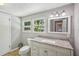 Bathroom featuring a granite-look vanity and well lit with windows at 6006 N Highland Ave, Tampa, FL 33604