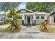 Charming green home featuring a black door, front yard plants, and a quaint front porch at 6006 N Highland Ave, Tampa, FL 33604