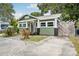 Green home featuring a black door, front yard plants, quaint front porch, and wood fence at 6006 N Highland Ave, Tampa, FL 33604