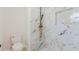 Modern bathroom featuring elegant marble tile and rainfall shower head with gold-tone fixtures at 6110 16Th St, Zephyrhills, FL 33542