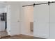 Hallway featuring modern flooring and a sliding barn door to a bathroom at 6110 16Th St, Zephyrhills, FL 33542